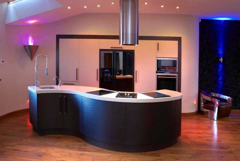 A bespoke Fitted kitchen in Yarm , with an s shaped island in wenge doors an da light worktop , with a tall isolated bank of tall cabinets housing fridge freezer and oven and microwave