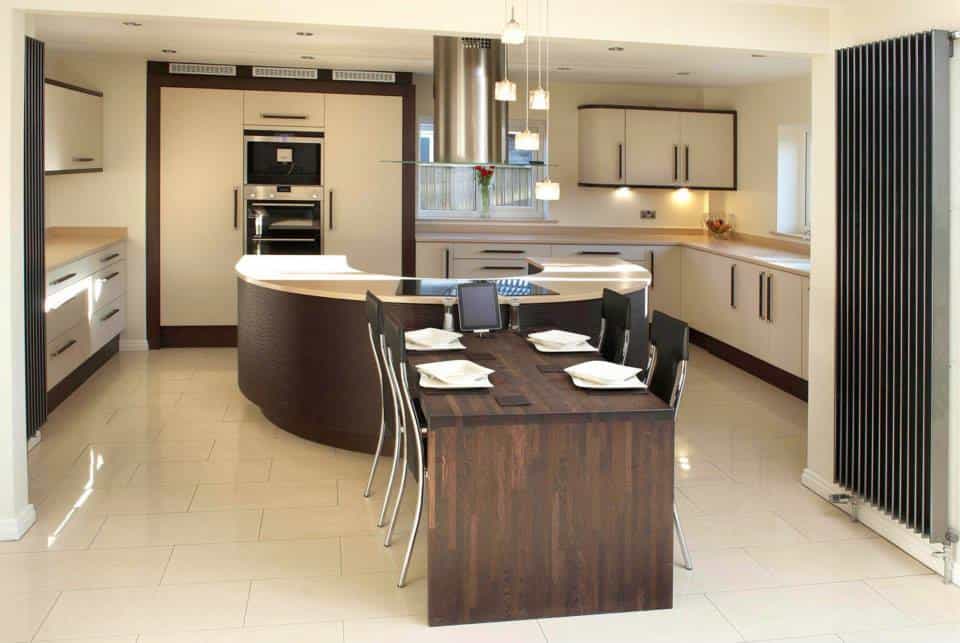 fitted kitchen in Teesside with a timber table fixed to a u shape island with a hob , to th erear tall cabinets with fridge an dfreezer hisdden an dovens at a height , wenge and porcelain doors all wrapped in wenge frame