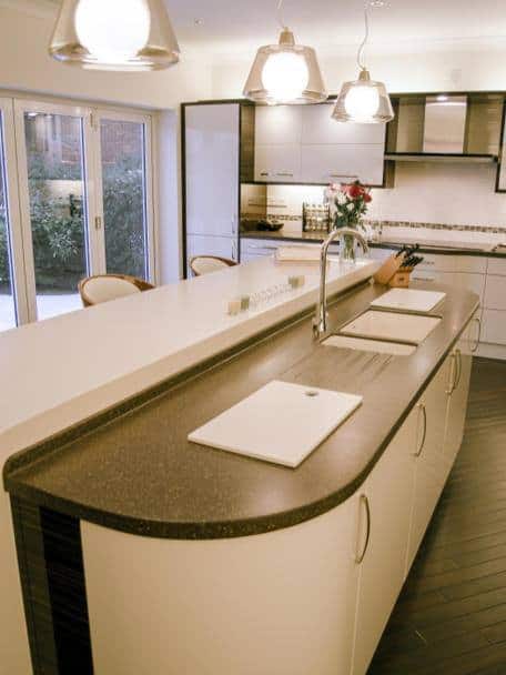 beige cabinets with sink below a window ebony worksurfaces above with pendant lighting