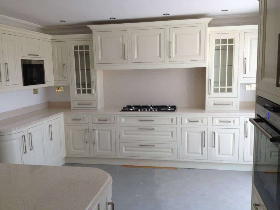 An Astor kitchen having light coloured doors and light worksurface which reflect the light back into the room, dresser cabinets with glass frame a mantle area which has drawer cabinets below an da hob in the light coloured worktop, Milne Kitchen,