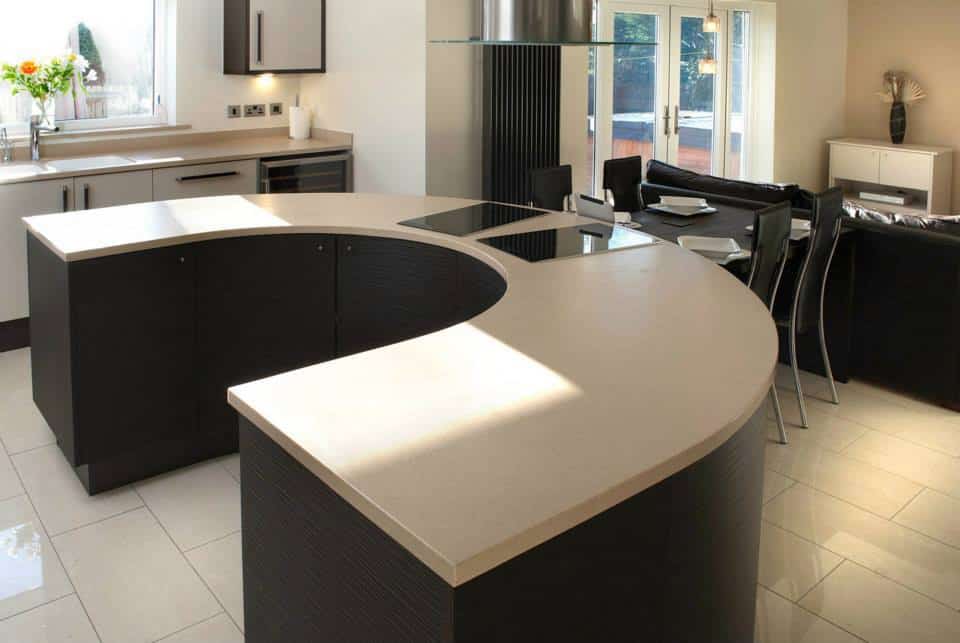 fitted kitchen in teesside showing wenge island in a u shape and corian light worksurfaces with hob above , casual seating to the background, Clydesdales Kitchen,