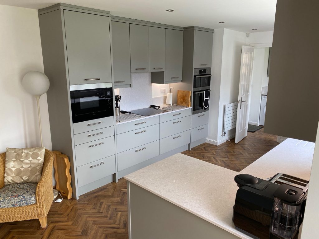 Fitted kitchen in Teesside by Court Homemakers with two tall cabinets for ovens either side of two sets of wide drawers where a hob is centralised