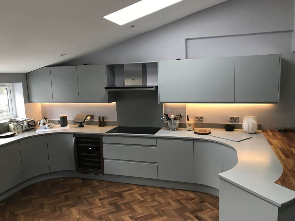 curved base cabinets and to the left wide drawer below a induction glass hob with extractor above