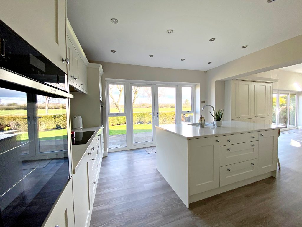 An island with sink and chrome tap , oak effect cabinets below with drawers and cupboards, patio doors to the background