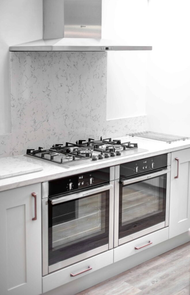 two built under ovens side by side and a large gas hob above , grey cabinets to the left and right