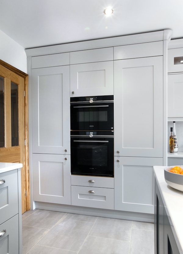 Fitted kitchen in Dove grey with an oven tower frame swith a larder cabinet to th eleft hand side and a fridge tower to the right hand side