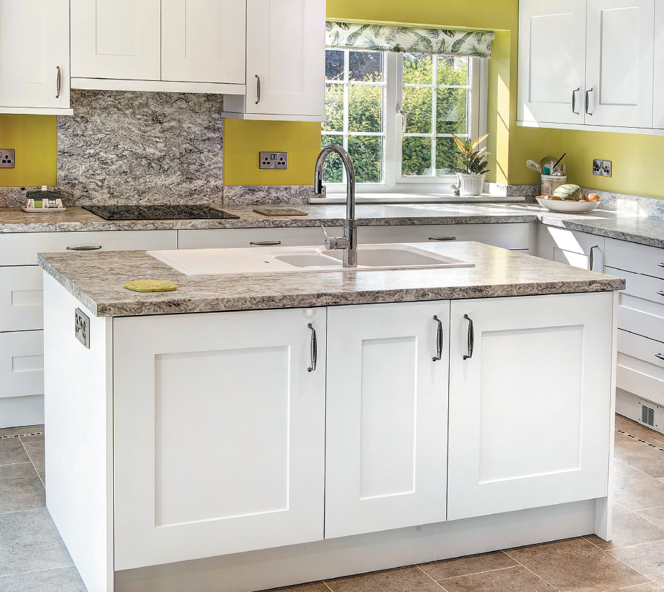 fitted kitchen with unit sin cream , sink in the centre and bold darker tops , cabinets below in cream