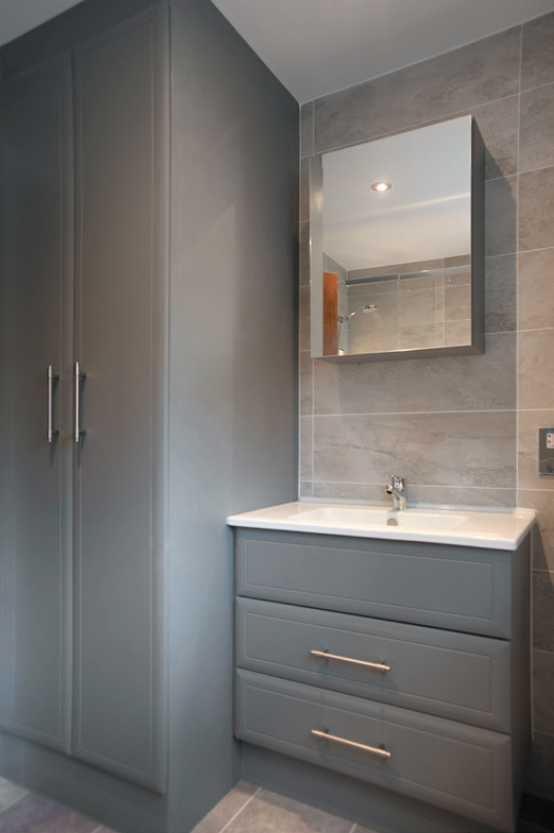 fitted bathroom cabinets in grey and vanity sink below a wall mirror, Williams Kitchen,