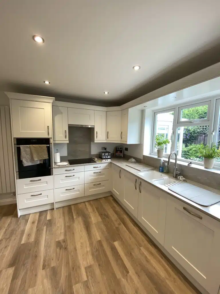 Sleek Stylish Kitchen Designed And Installed with tall oven tower drawers below a hobs and a sink with storage below a large window